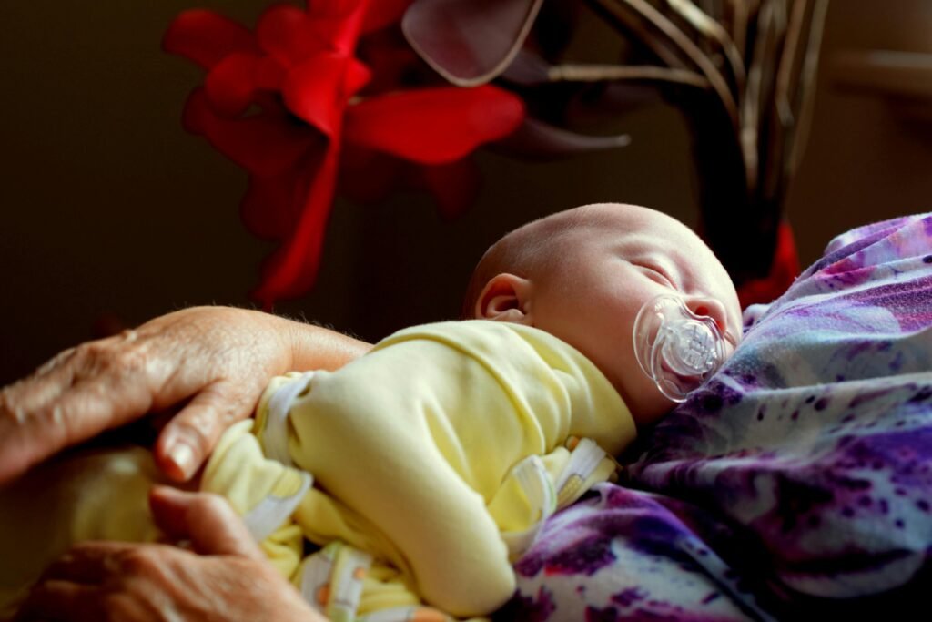 pexels-photo-1581281-1581281 A peaceful newborn sleeping in a woman's embrace, surrounded by cozy warmth.