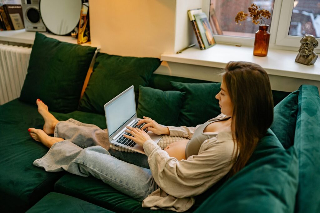 Expectant mother comfortably working from home on a laptop, showcasing modern maternity lifestyle.