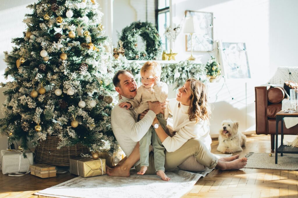 A joyful family sitting by the Christmas tree with their dog, enjoying the festive season indoors.